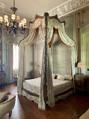 Elegant bedroom with a four-poster bed draped in sheer white curtains and classic Italian artwork.