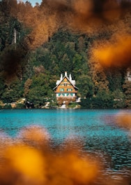 Cozy lakeside house with wooden shutters and blooming flowers in spring.