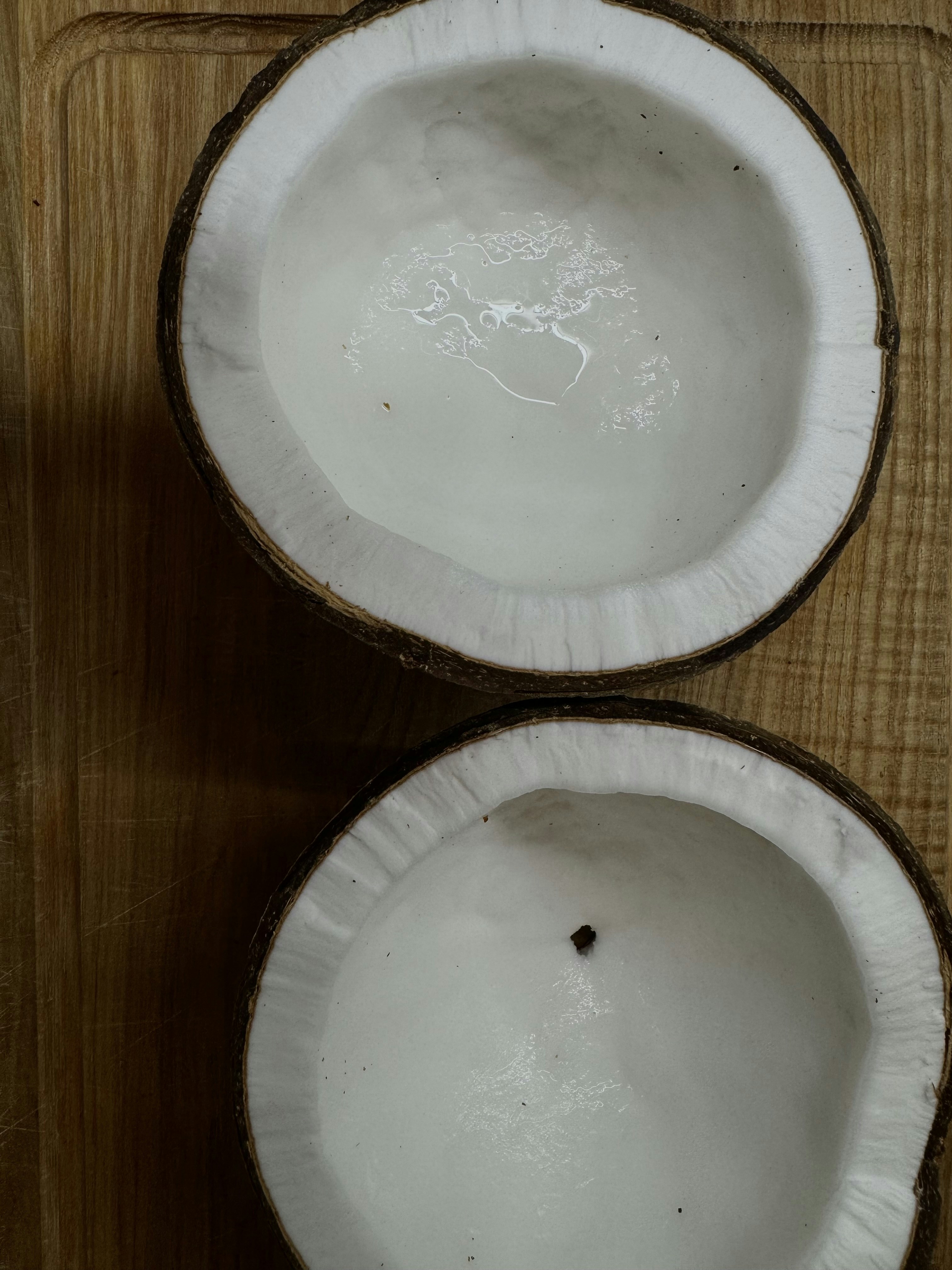 Fresh coconut halves and desiccated coconut flakes on bright white surface