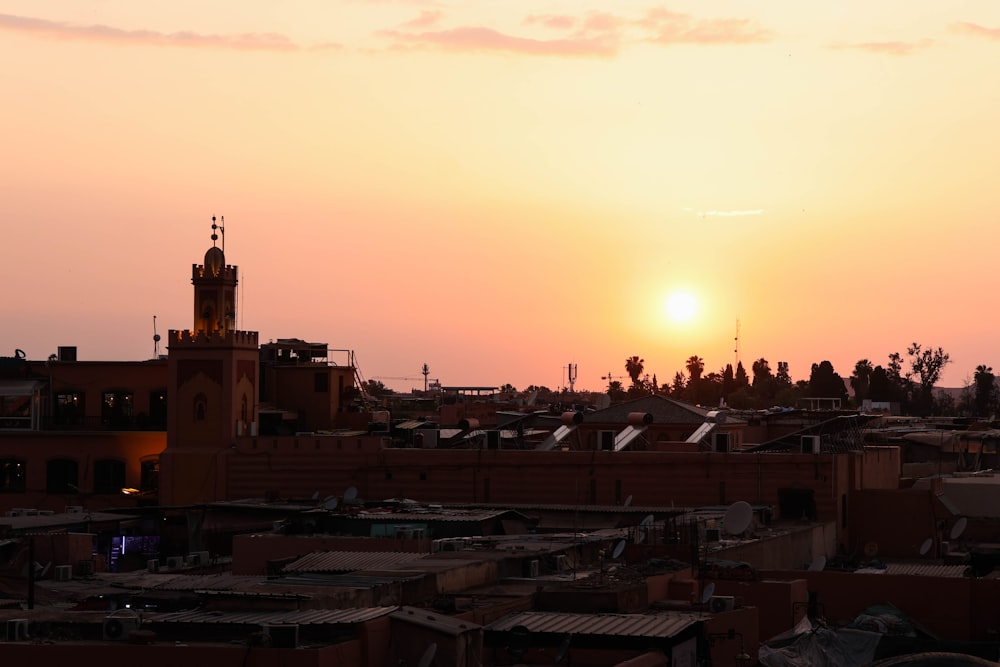 the sun is setting over a city with rooftops