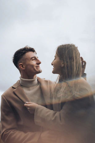 Warm, spontaneous portrait of a couple sharing a quiet moment outdoors in soft terracotta tones.