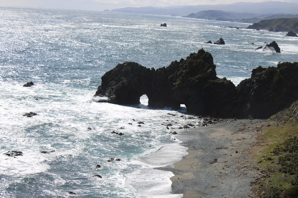 ein Strand mit einer Felsformation mitten im Wasser