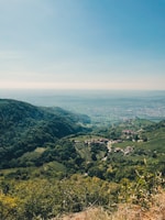 A happy traveler enjoying a scenic view from a hilltop overlooking vineyards and rolling hills.