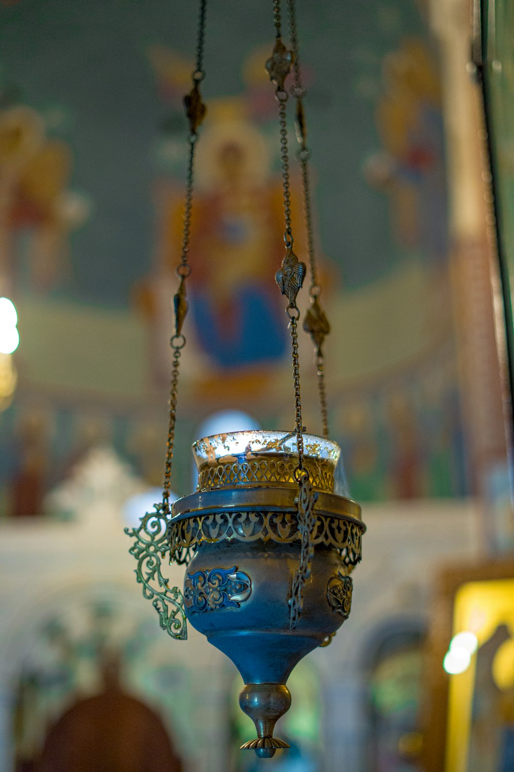 a blue vase hanging from a chain in a church