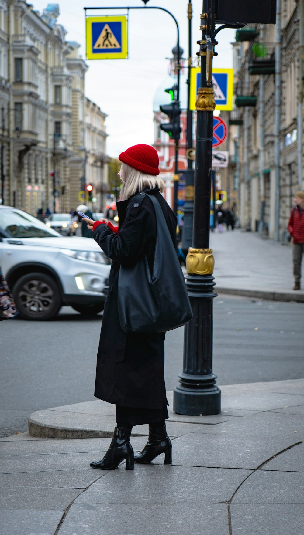 a woman standing on a street corner looking at her cell phone