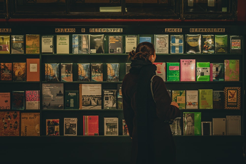 a woman standing in front of a wall of books