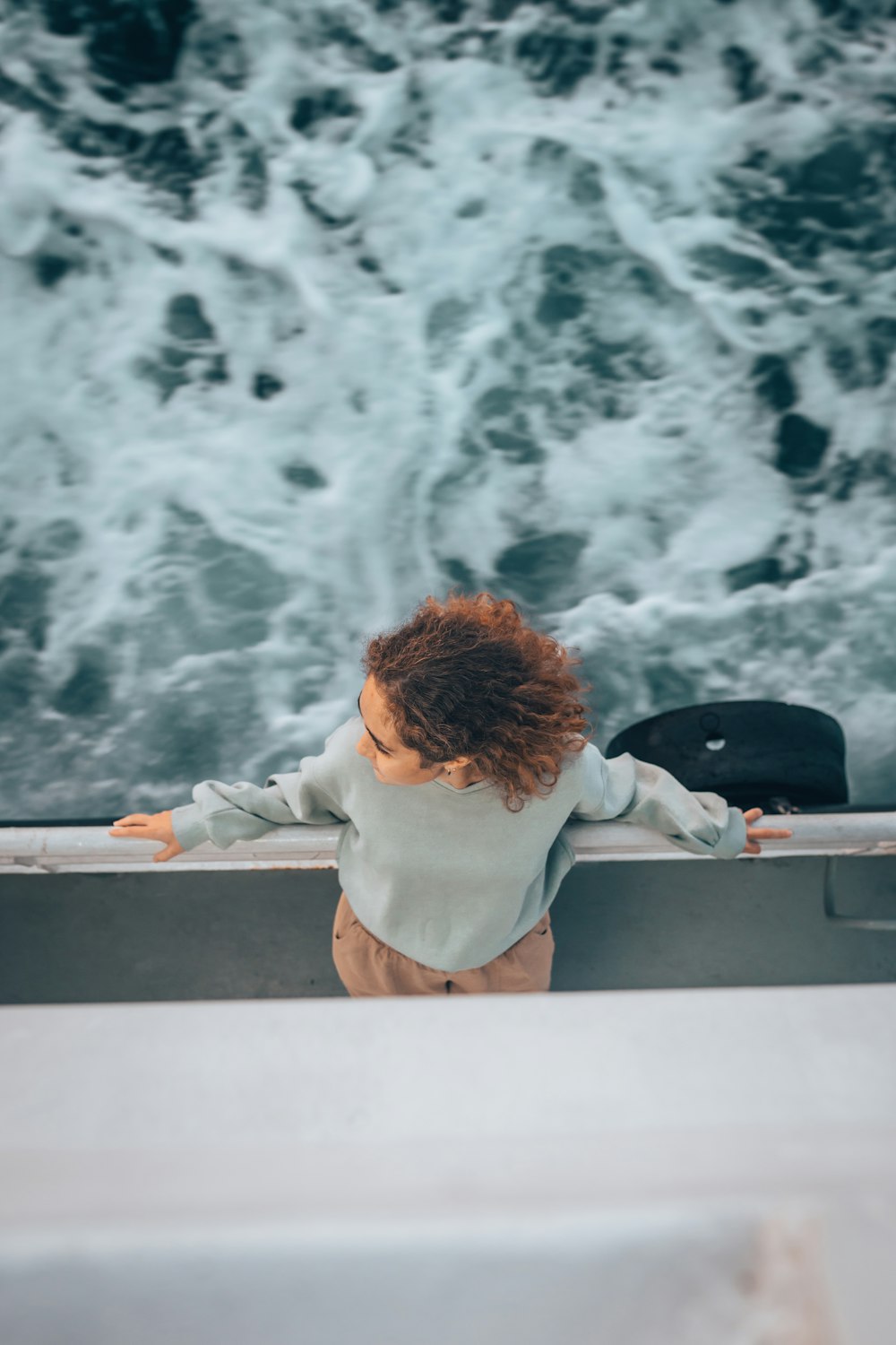 a young child standing on a boat looking out at the ocean