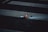 A lit object, possibly a firework or a smoking item, on a dark street segmented by cracks and white pedestrian crossing lines. The object is emitting a small flame and some debris is scattered around it.