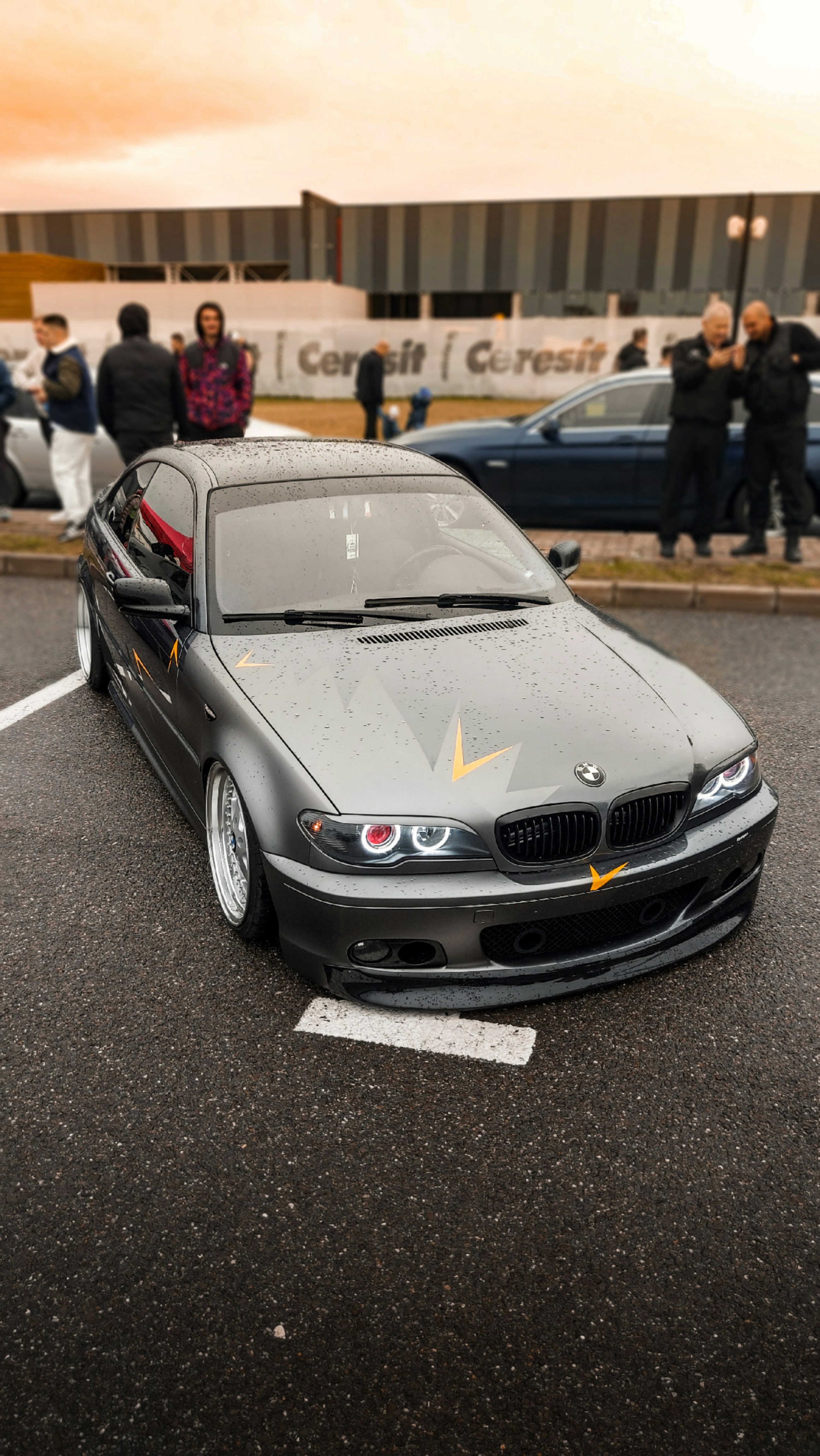 a car parked in a parking lot with people standing around