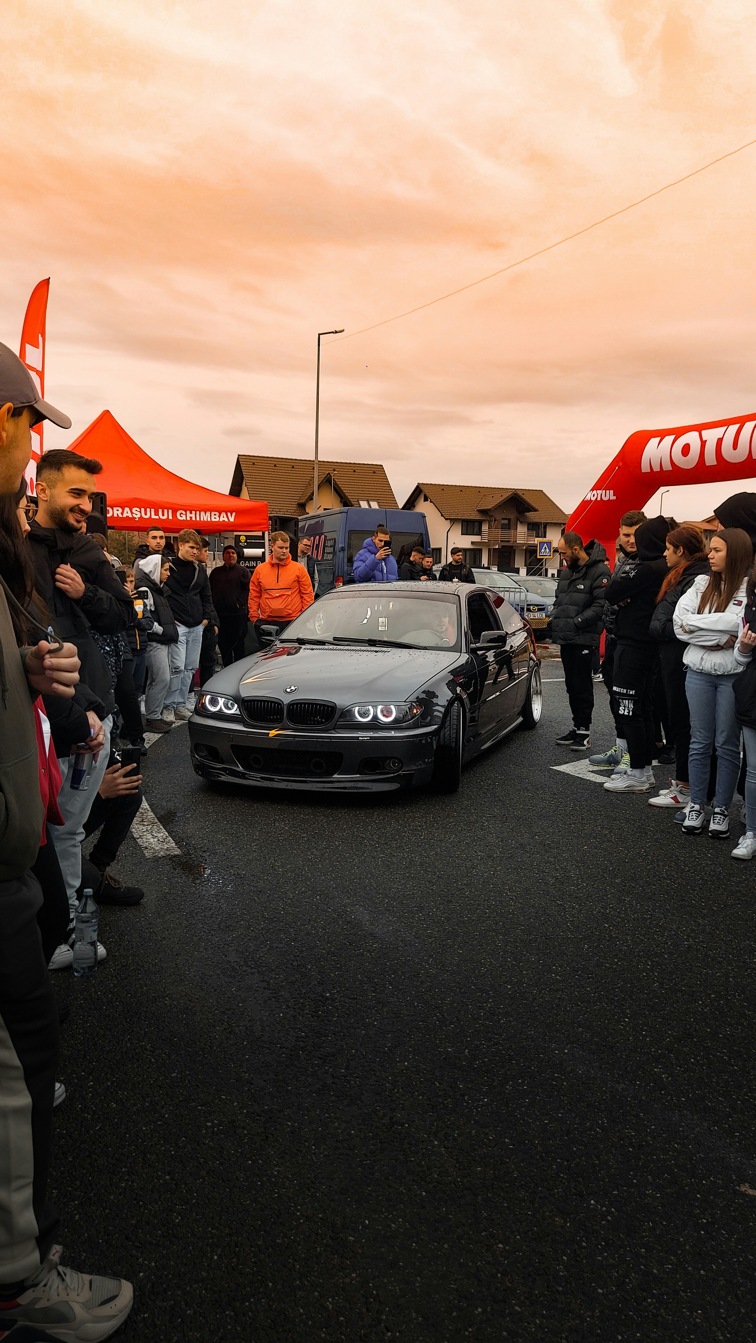 a group of people standing around a black car