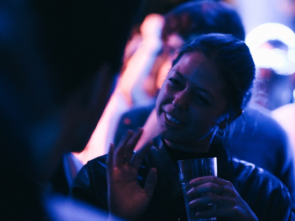 a woman smiling and holding a glass in her hand