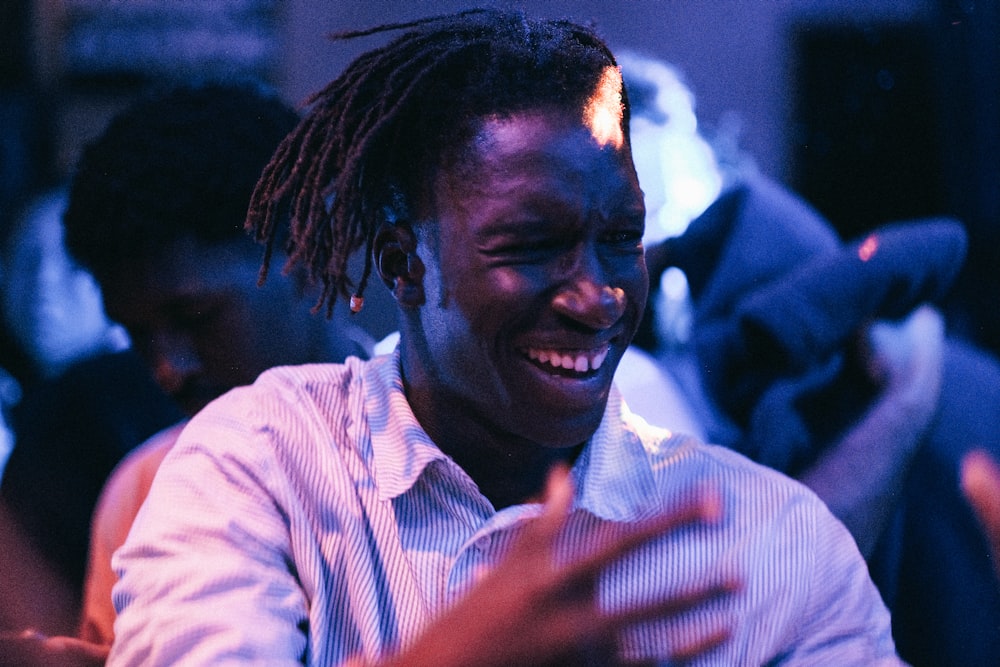 a smiling man with dreadlocks sitting in a room