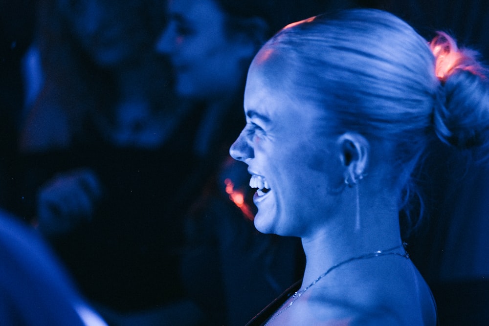 a woman smiling in a dark room with other people