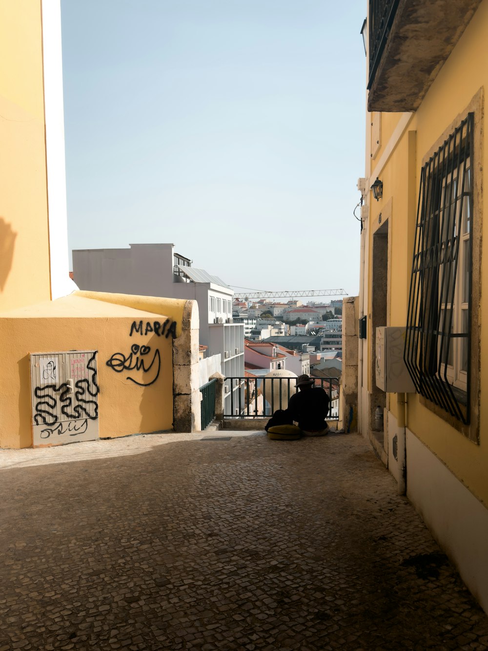 a man sitting on the side of a yellow building