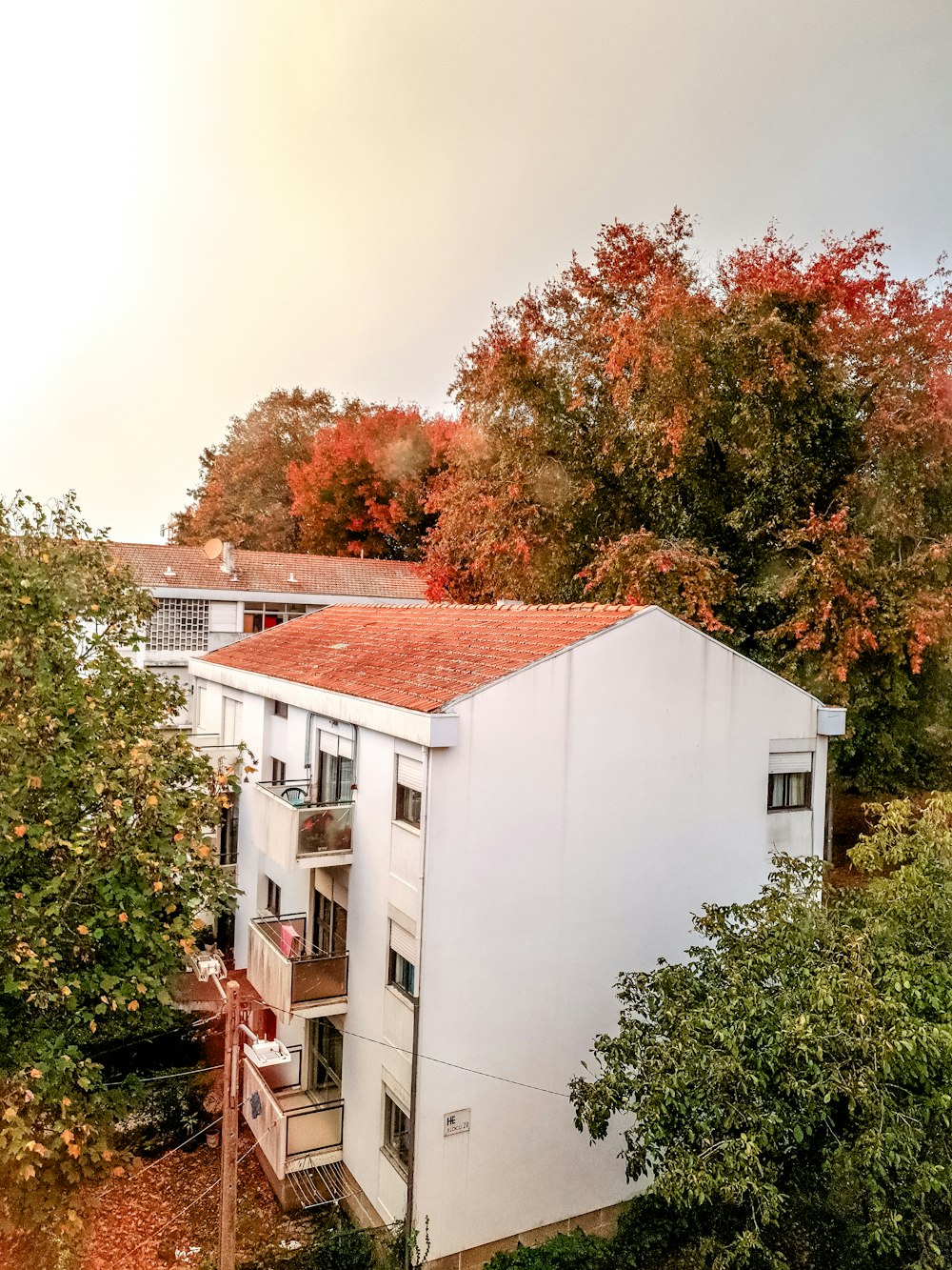 a white building with a red roof surrounded by trees