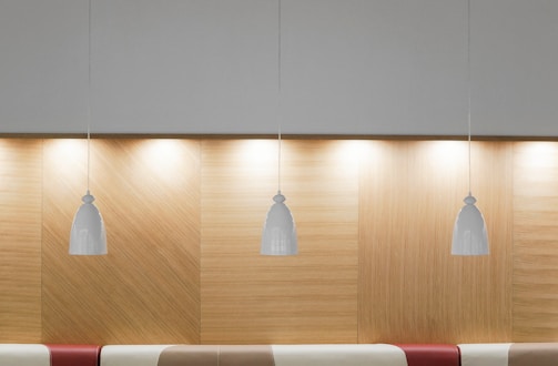 A minimalist dining area illuminated by a cluster of warm, golden pendant lights.