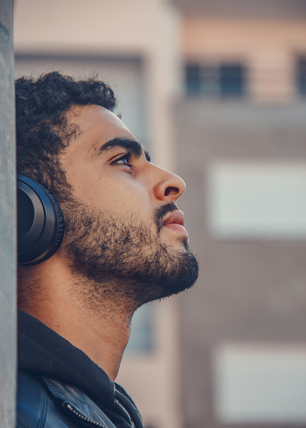 a man wearing headphones leaning against a wall