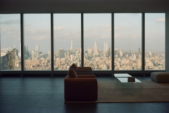 A sleek living room in a high-end apartment overlooking a European city skyline at sunset.