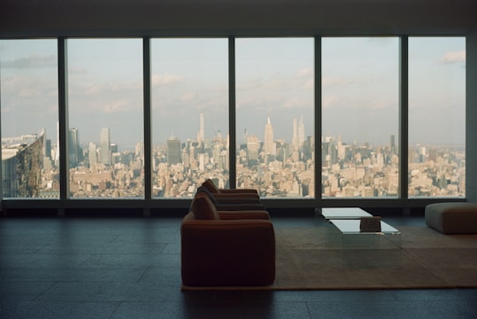 A bright NYC apartment living room with large windows and city skyline views.