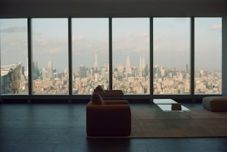 A bright, modern living room with large windows showcasing a city skyline view.