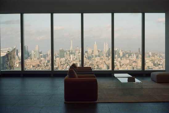 A bright, modern living room with large windows showcasing a beautiful city view.