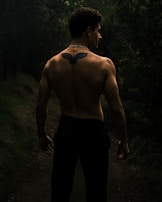 Full back tattoo showing a night forest scene with moonlight and mist.