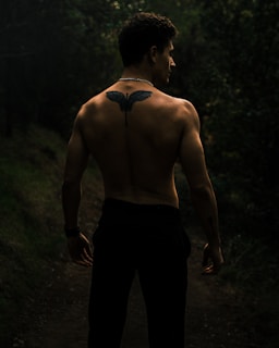 Full back tattoo showing a night forest scene with moonlight and mist.