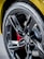 A close-up view of a car tire with a glossy black alloy wheel. The tire has the word 'Eagle' printed on it, and the wheel features a prominent black five-spoke design with a logo in the center. Behind the wheel, a red brake caliper is partially visible.
