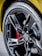 A close-up view of a car tire with a glossy black alloy wheel. The tire has the word 'Eagle' printed on it, and the wheel features a prominent black five-spoke design with a logo in the center. Behind the wheel, a red brake caliper is partially visible.