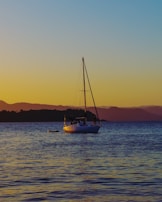 A liveaboard boat anchored in calm blue waters under a golden sunset.