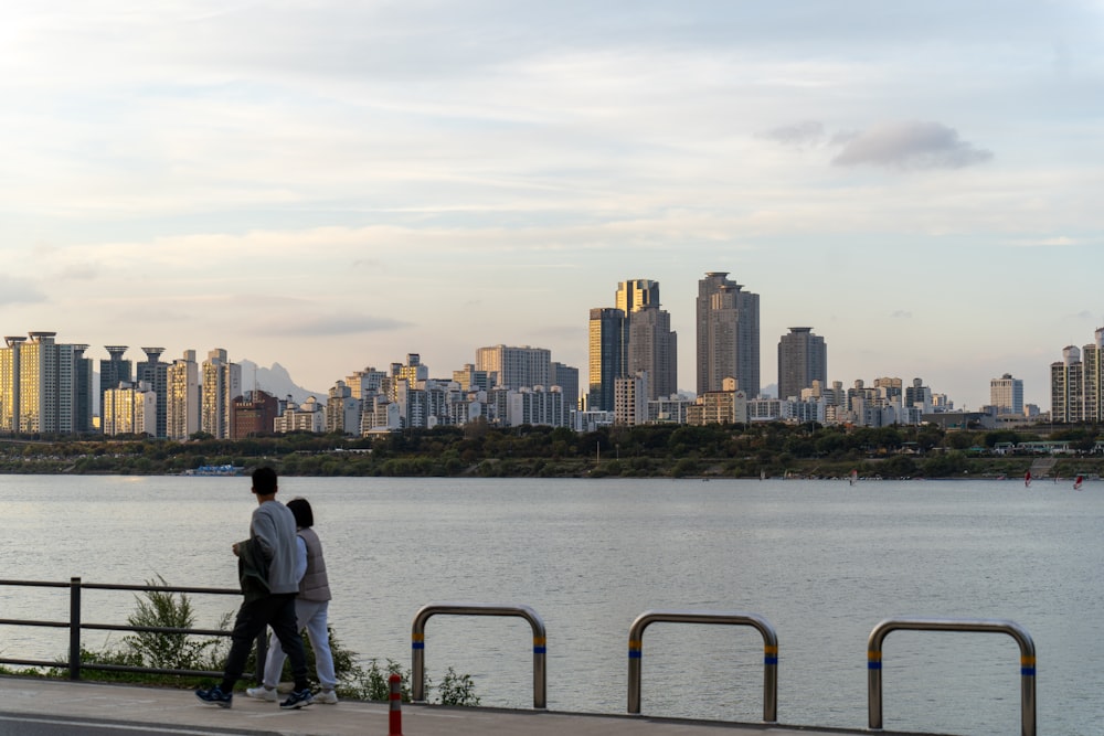 a man and a woman are walking by the water