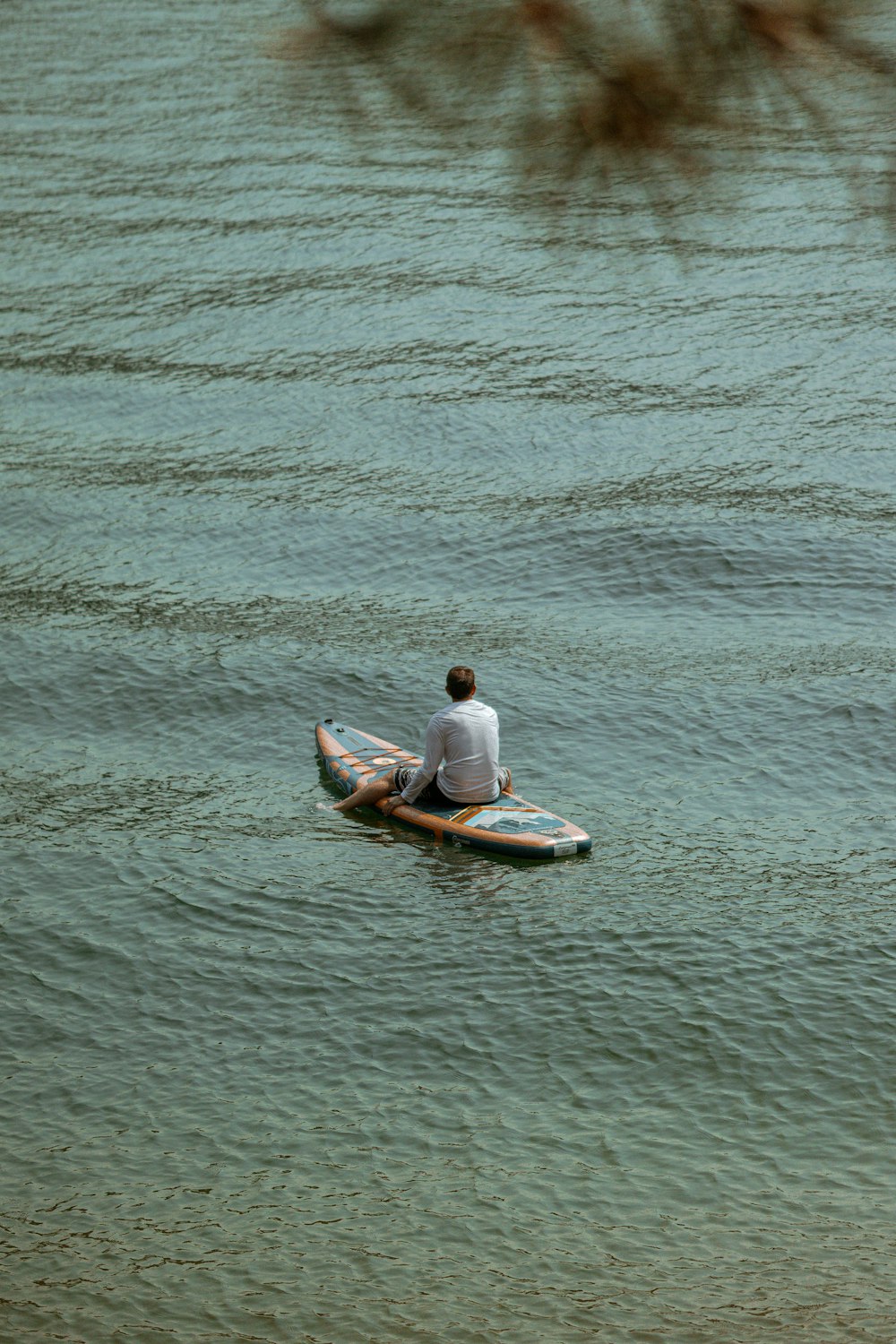 um homem sentado em uma prancha de surf na água