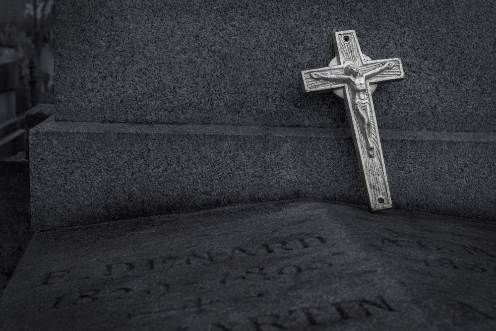 a black and white photo of a cross on a grave