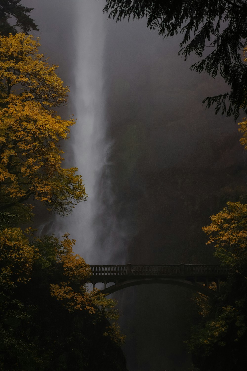 eine Brücke über einen Fluss mit einem Wasserfall im Hintergrund