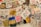 A collection of vibrant, hand-painted art pieces and illustrations on fabrics, featuring a mix of abstract designs, text, and depictions of various subjects. Some fabrics include written messages in different languages, alongside colorful imagery including hearts, eyes, faces, and various symbols.