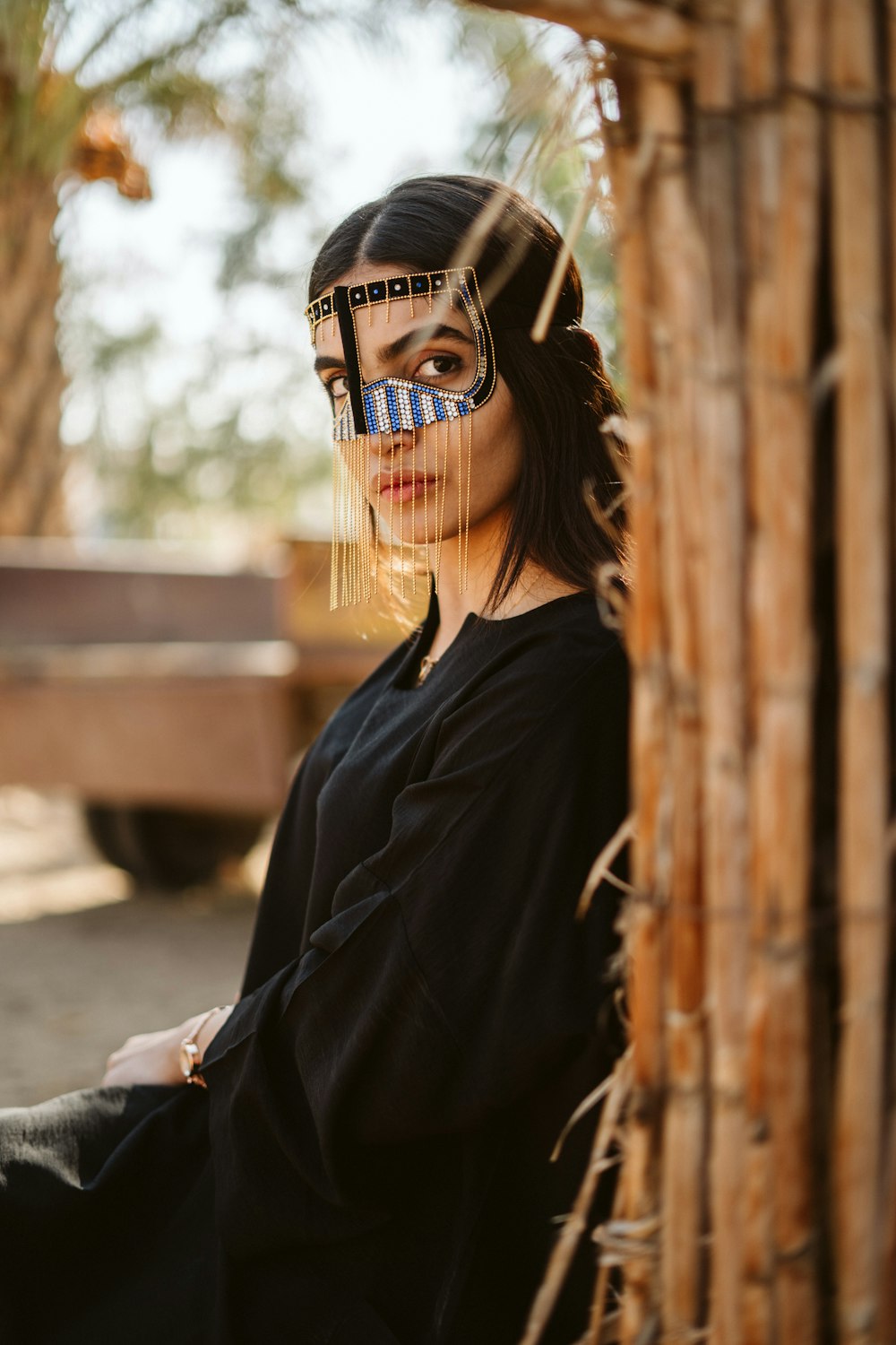 a woman with a mask on her face standing in front of a bamboo structure