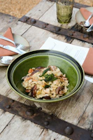 A rustic wooden table set with a steaming plate of spaghetti carbonara topped with parsley.