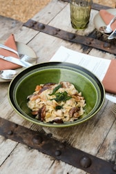 A rustic table set with wine glasses and plates of homemade pasta.