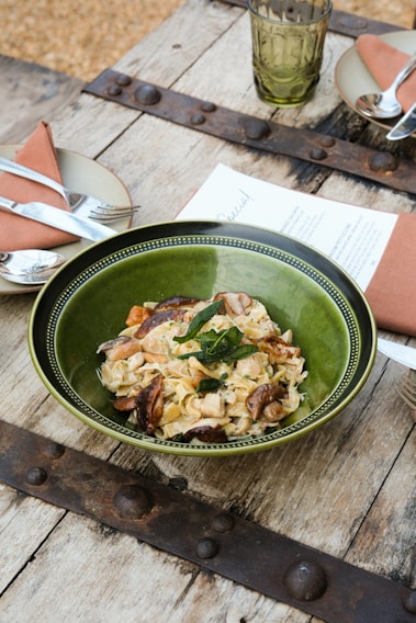 A beautifully set rustic Italian dining table with pasta and wine.