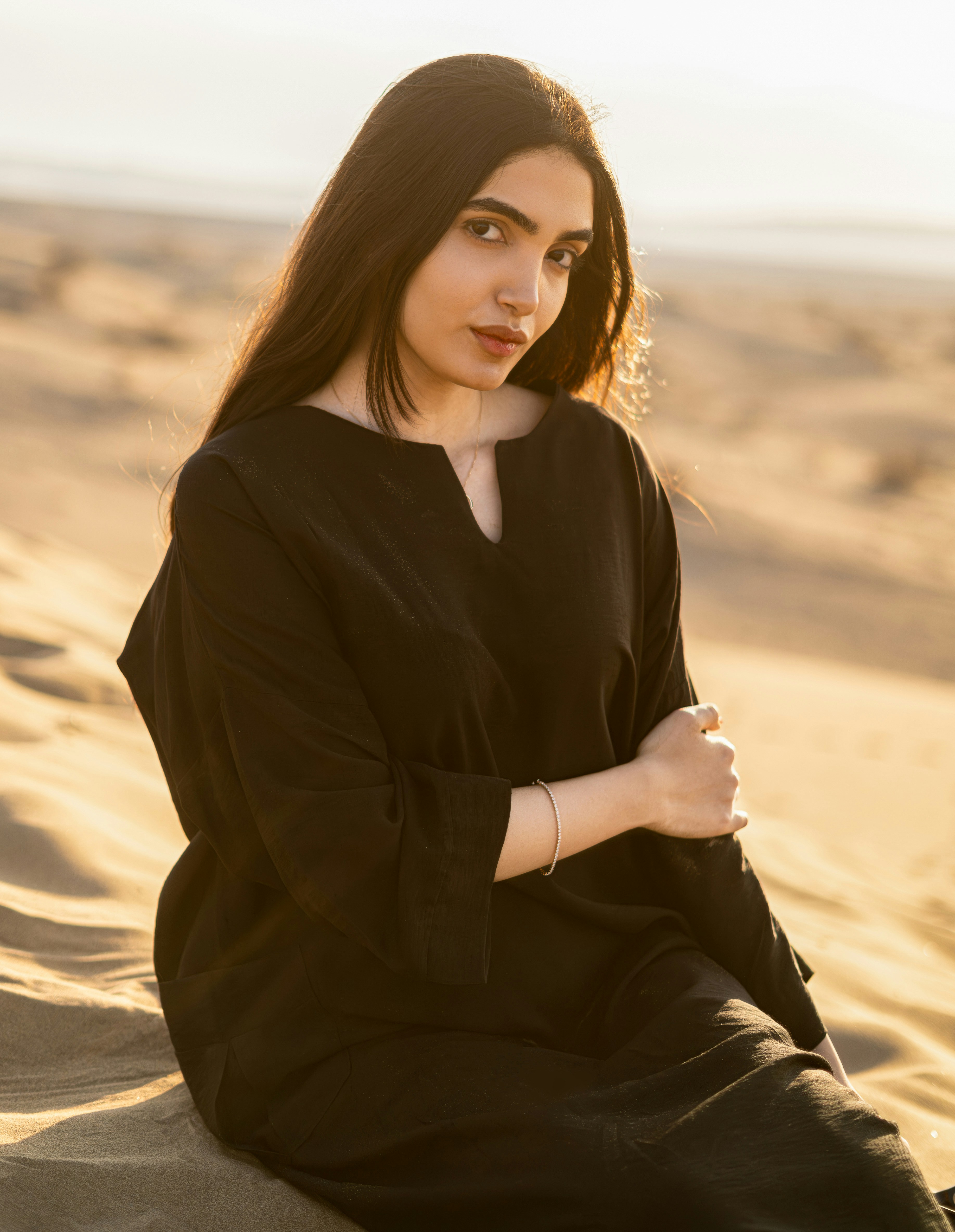 una donna seduta in cima a una spiaggia sabbiosa