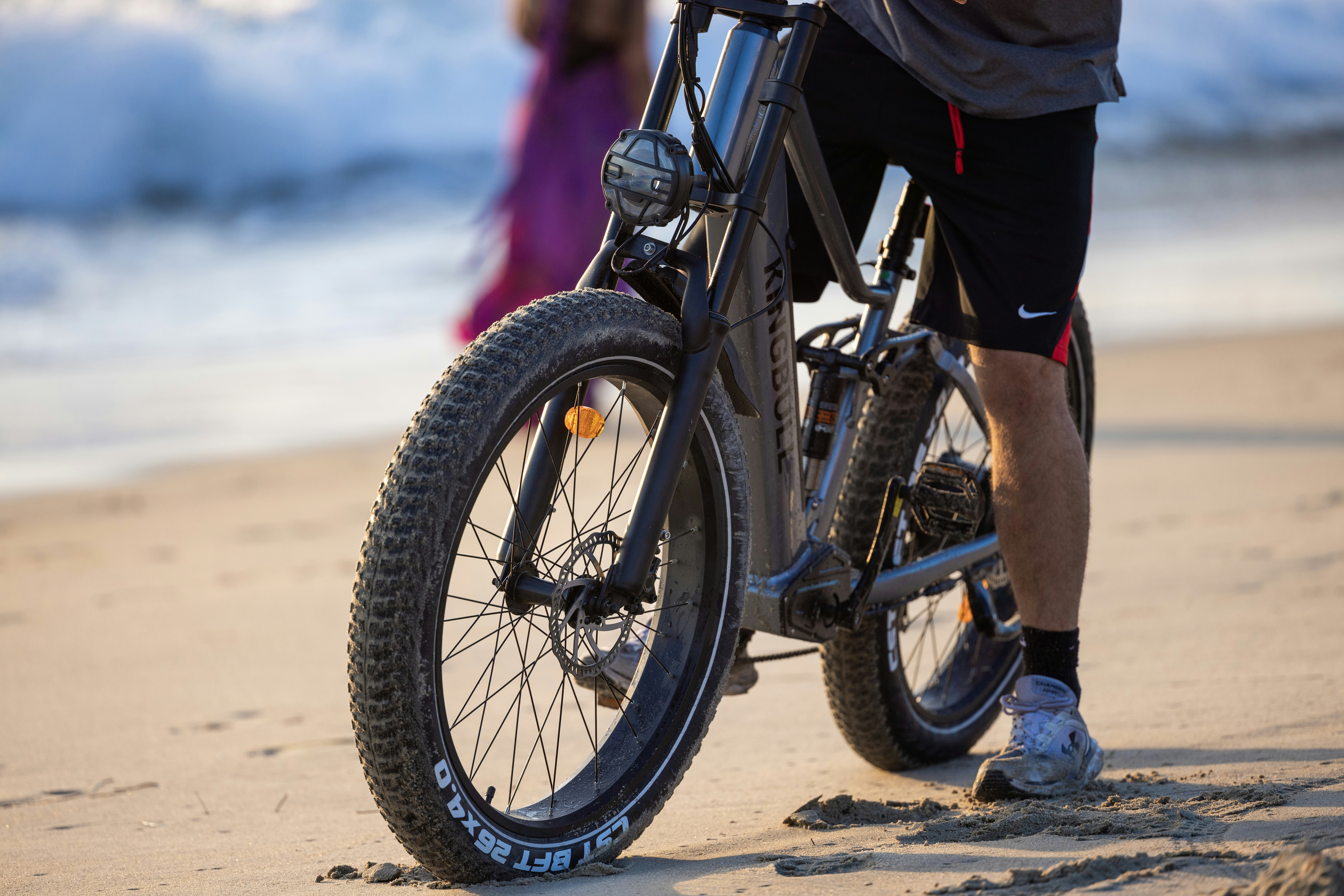 Un hombre montando en bicicleta en la parte superior de una playa de arena