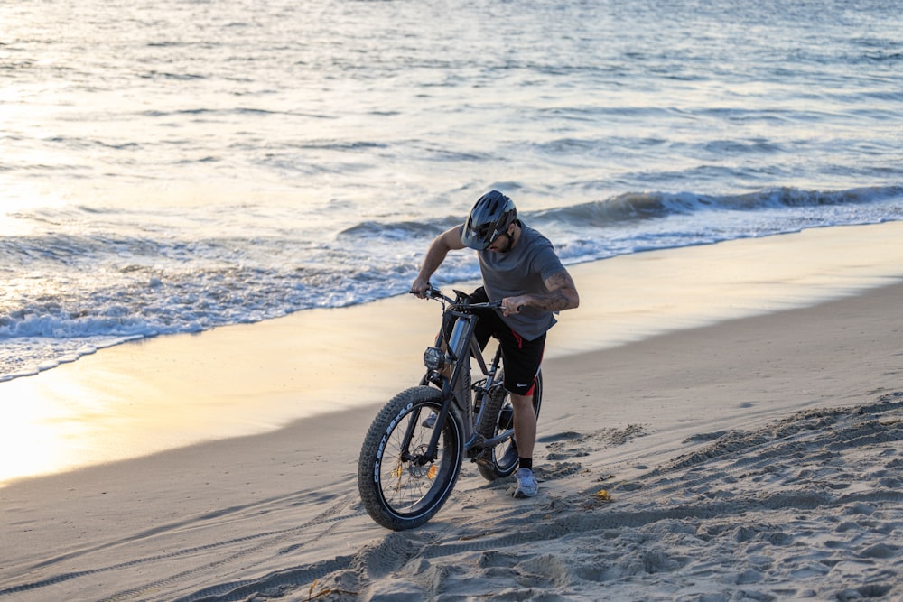 a man riding a bike on top of a sandy beach