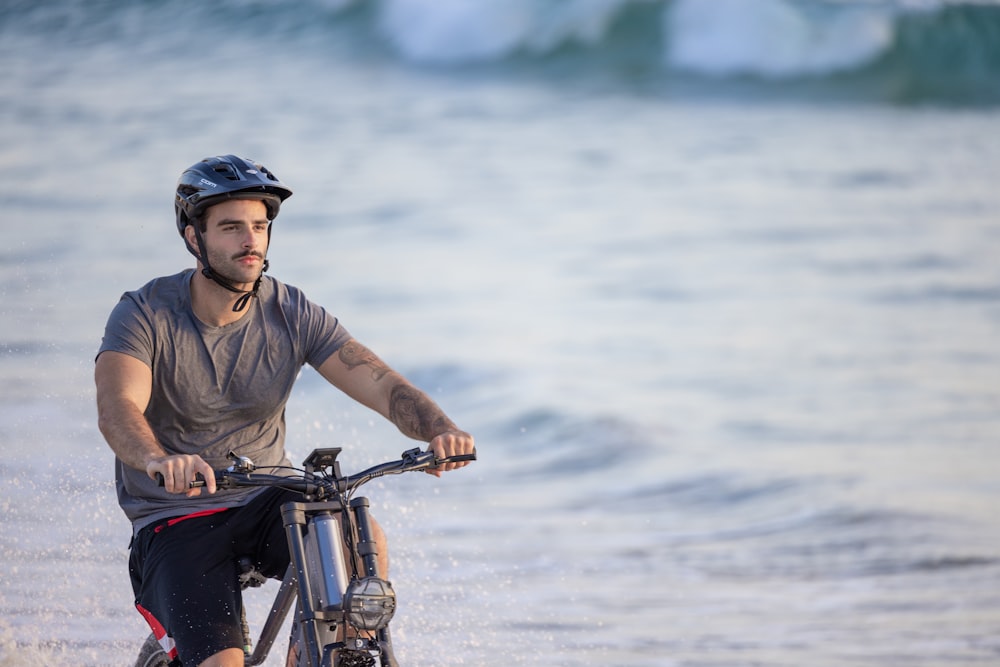 un uomo in sella a una bicicletta sulla spiaggia