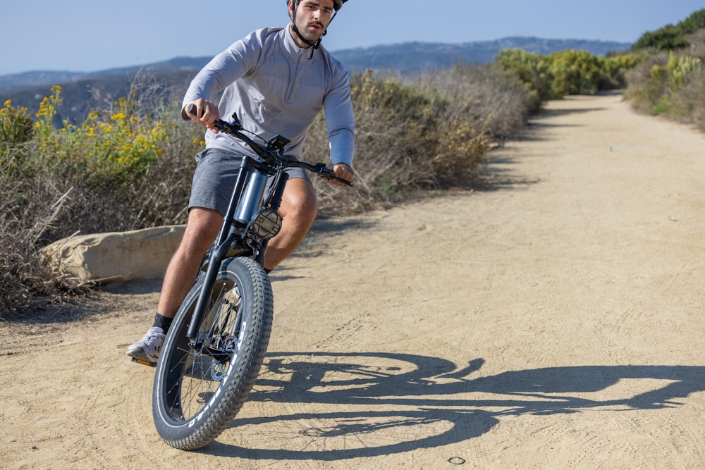 a man riding a bike down a dirt road