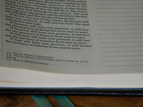 A close-up view of an open book showing printed text on the left page. The text has a formal layout with paragraphs and a section of footnotes at the bottom. The right side of the image shows a portion of blank pages with dotted lines, possibly for writing notes.