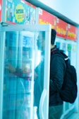 Technician inspecting a refrigerated display case in a retail environment.