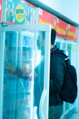 Technician inspecting a refrigerated display case in a retail environment.