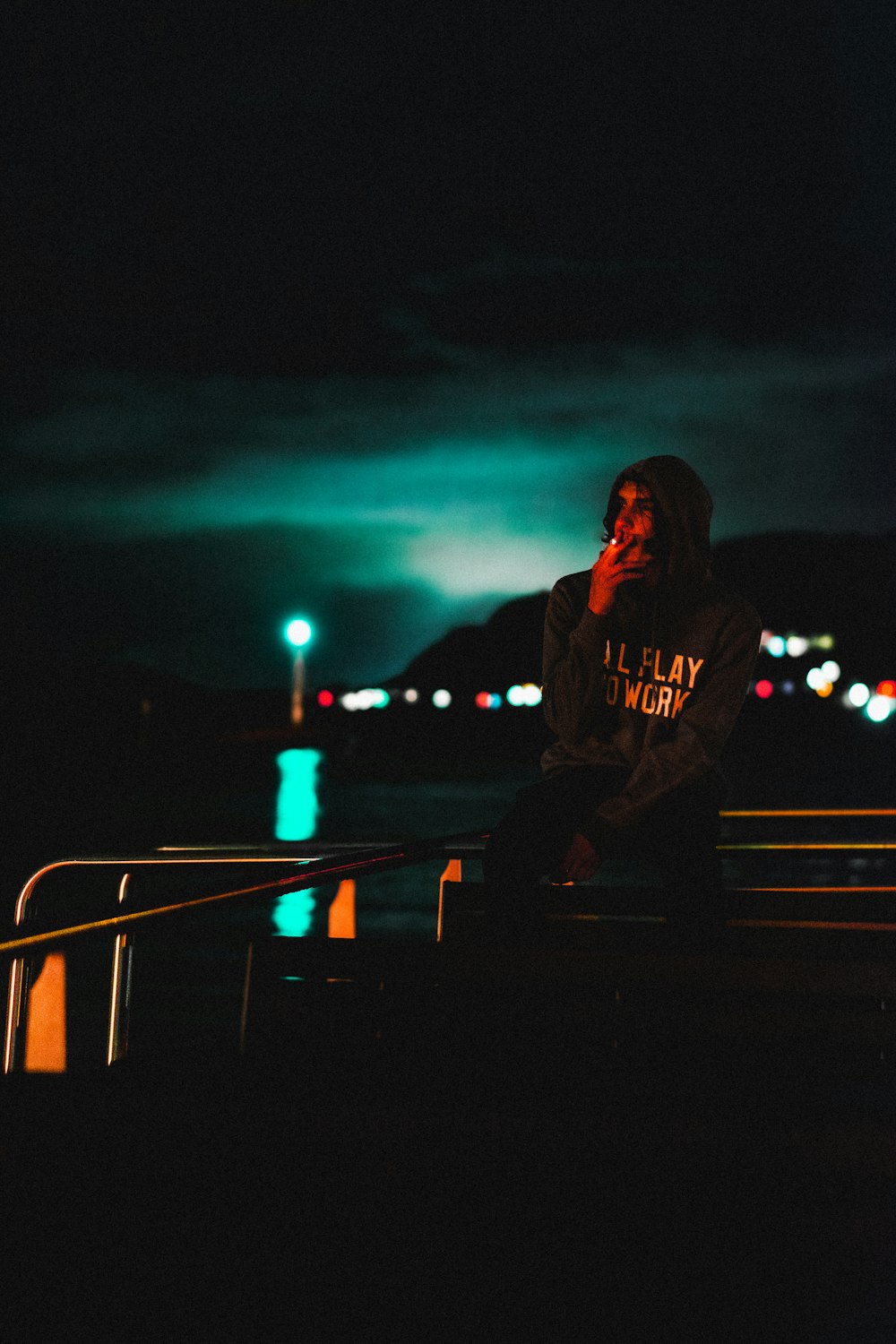 a person sitting on a rail in the dark