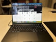 A laptop displaying a website with a search bar at the top and several categorized icons for different services. The laptop is positioned on a light-colored desk in an indoor setting, with the focus on the screen contents and some blurred background elements.