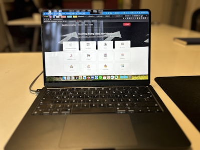 A laptop displaying a website with a search bar at the top and several categorized icons for different services. The laptop is positioned on a light-colored desk in an indoor setting, with the focus on the screen contents and some blurred background elements.